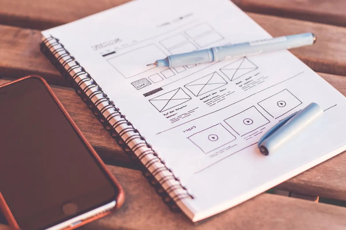 UI UX Design Company in Salem - Notebook with app wireframe sketches beside a smartphone
