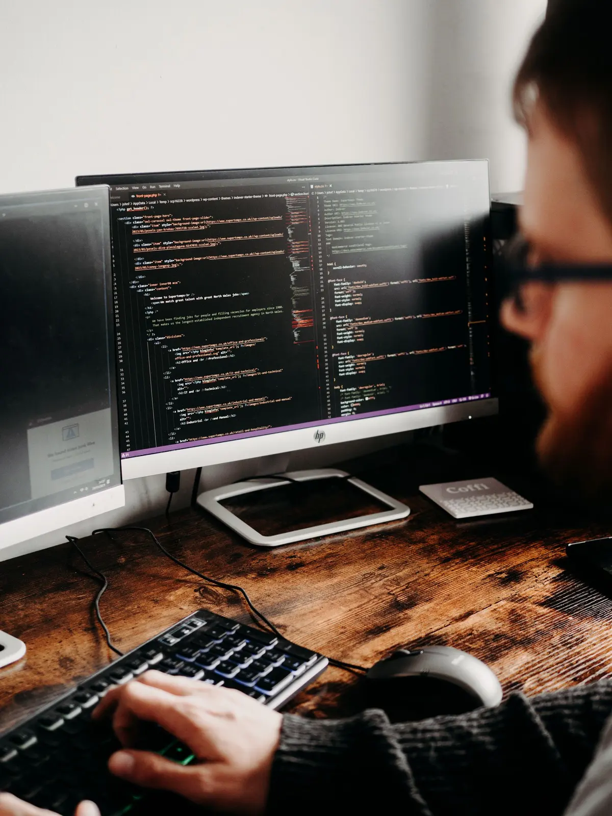 Website Development Company in Salem - Web developer writing code across multiple monitors